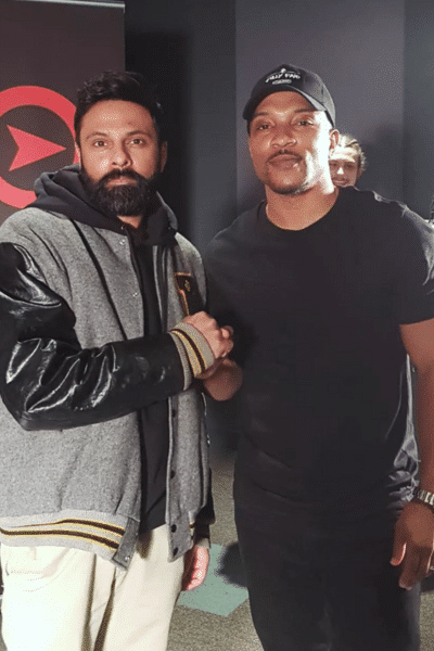 David Kukadia nd Ashley Walters shake hands in front of black curtain