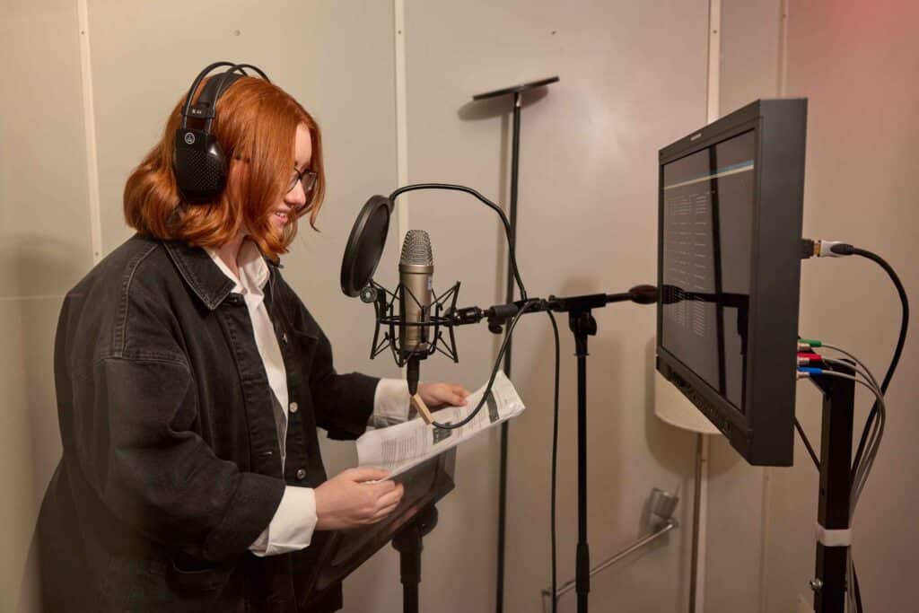 MetFilm School Ealing student using a microphone and teleprompter in a small studio