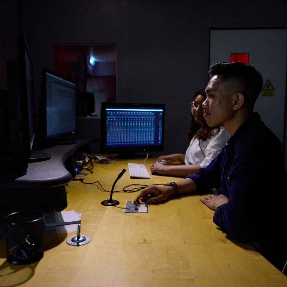 MetFilm School London students in a sound room with a microphone in front of them