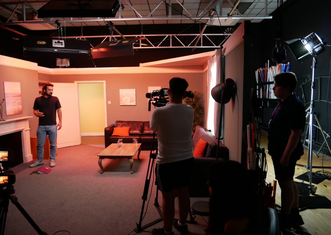 Three students in film set using film camera