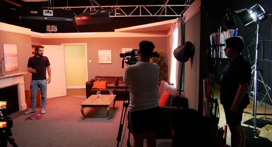 Three students in film set using film camera