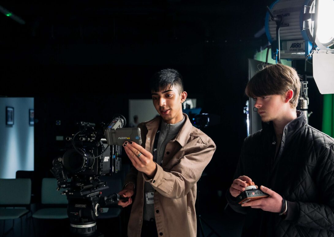 Two Manchester students adjusting film camera while on set